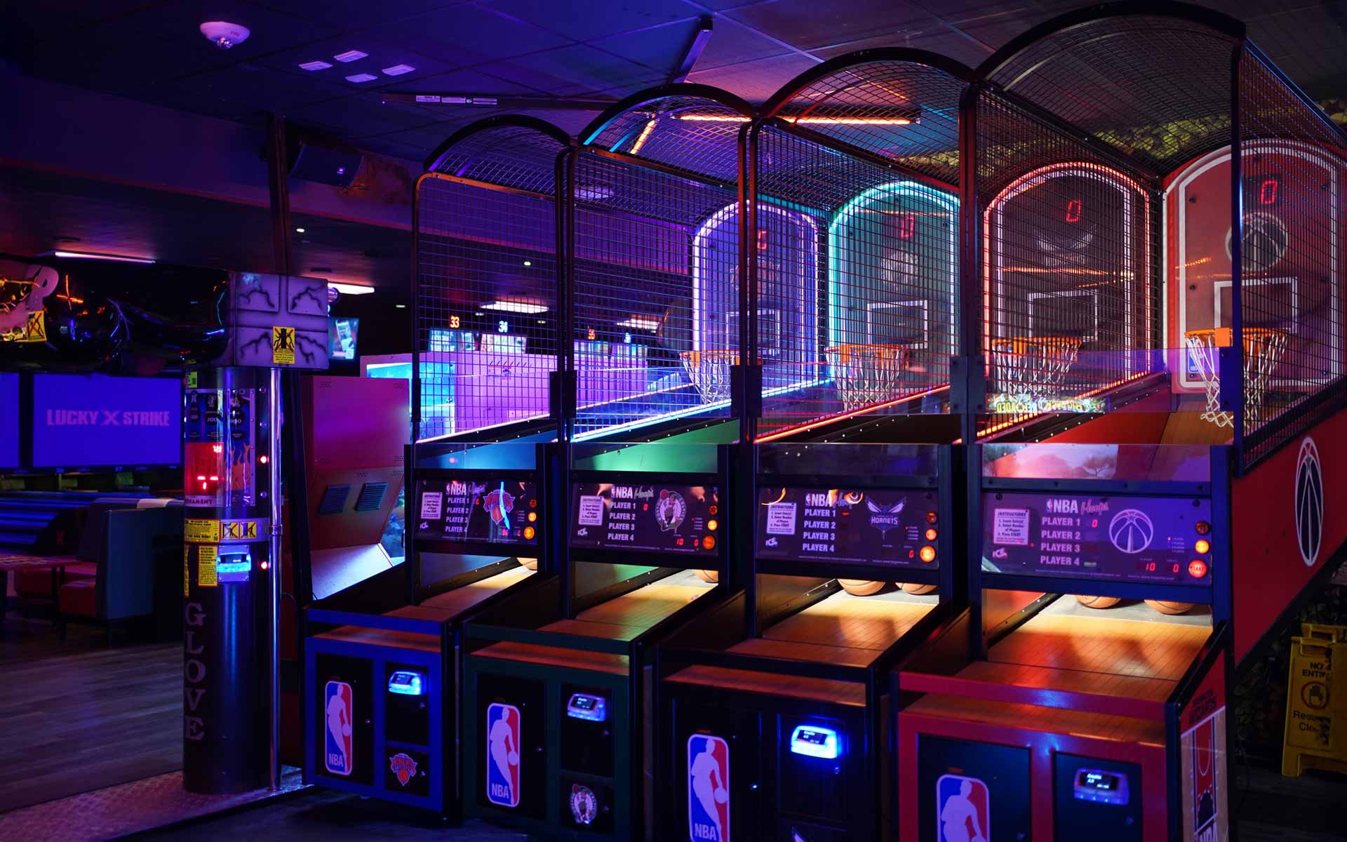 Arcade basketball shooting games at Lucky Strike with neon lighting and competitive multiplayer stations.