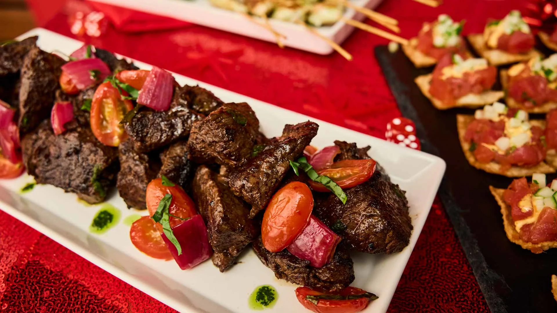 Seared steak bites with cherry tomatoes and herbs served as an event appetizer.