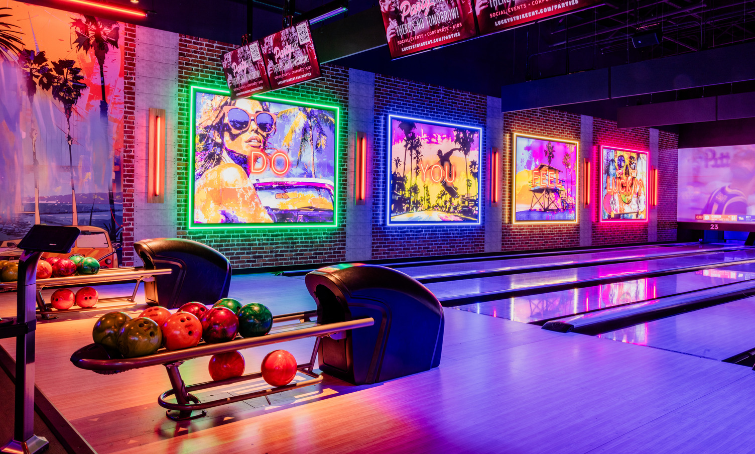 Neon-lit bowling lanes at Lucky Strike featuring vibrant wall art and a modern nightlife atmosphere.