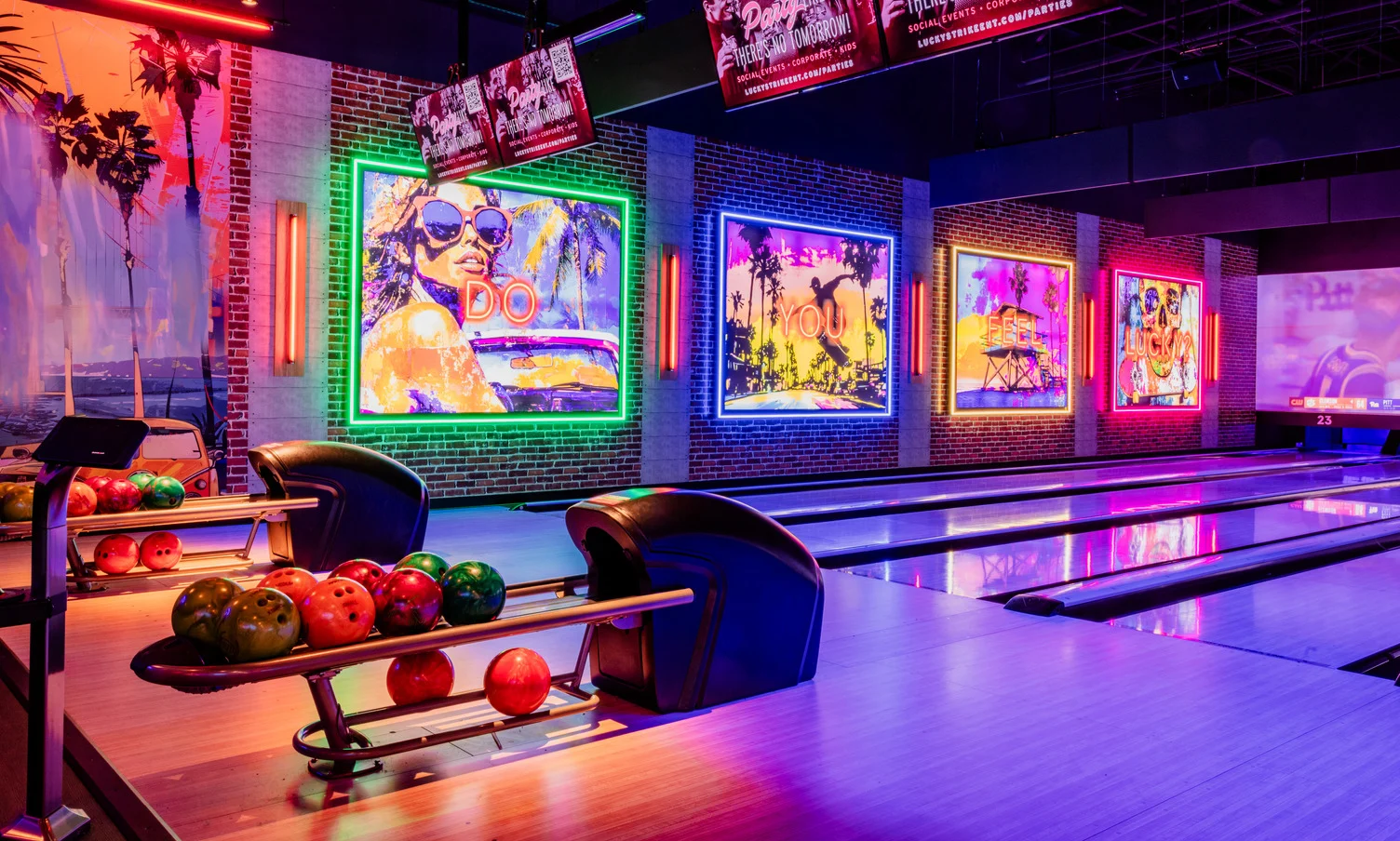 Neon-lit bowling lanes at Lucky Strike featuring vibrant wall art and a modern nightlife atmosphere.