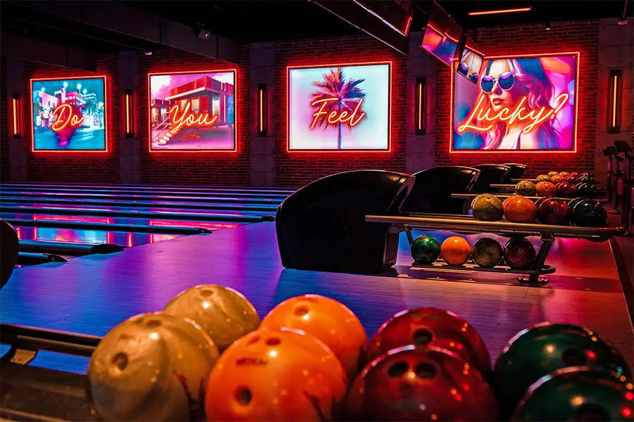 Colorful bowling ball on return rack with amazing bowling center and neon lights in the background
