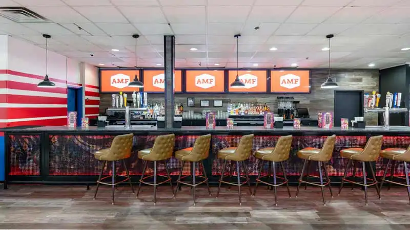Beautiful and spacious bar with with lots of seating and large TV screens above the bar.