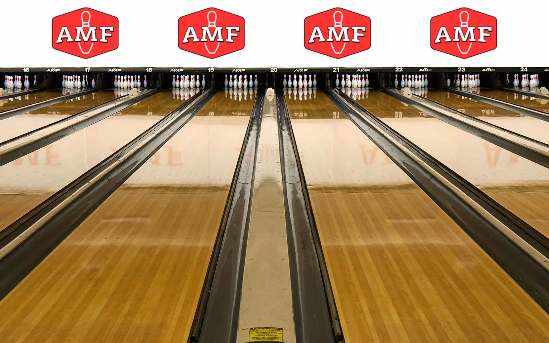Multiple bowling lanes at an AMF bowling center, viewed from the approach with pins set at the end and AMF logos displayed above each lane.