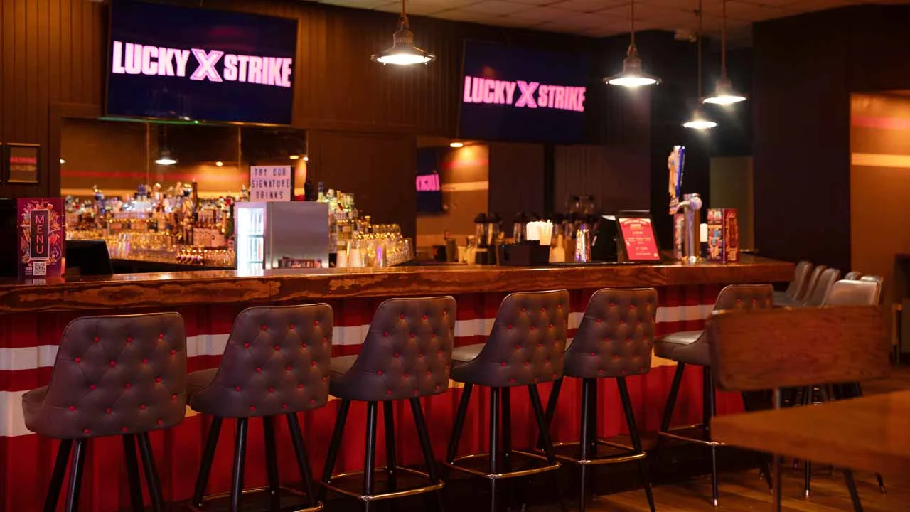 Lucky Strike Boca Raton bar with tufted leather stools, a fully stocked back bar, pendant lighting, and illuminated Lucky Strike signage