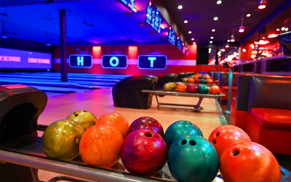 Colorful bowling balls lined up on bowling ball rack returns.