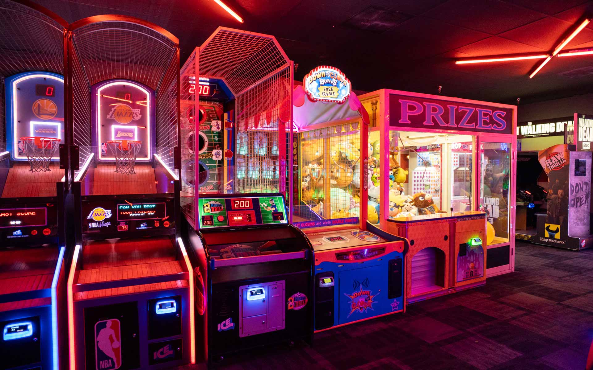 Colorful arcade at Lucky Strike featuring basketball hoops, ticket prize machines, and neon-lit games in a vibrant entertainment space.