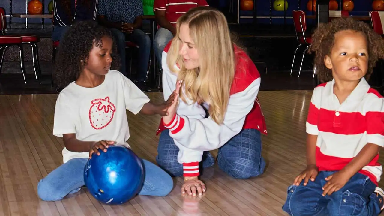 A mother slapping five with one of her sons on the approach of a bowling lane at AMF.