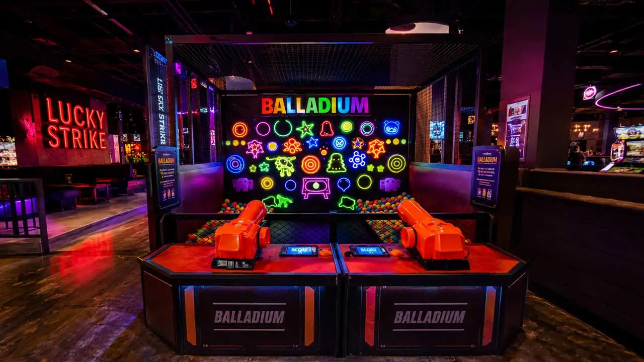Group of friends playing Balladium at a Lucky Strike location, aiming foam balls at a colorful neon target wall in a vibrant arcade setting.