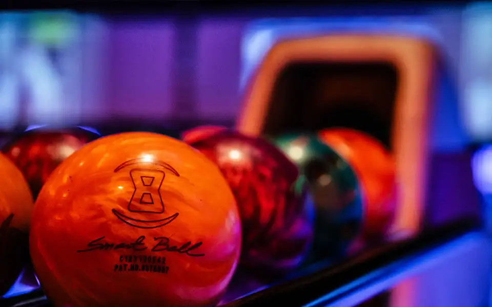 Closeup of colorful bowling balls lined up in the ball return