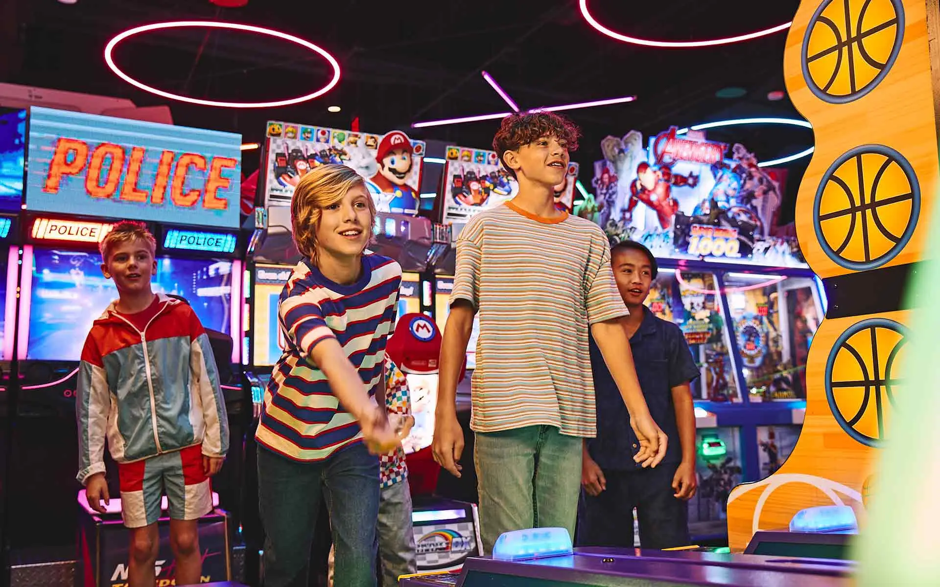 Kids playing arcade basketball and skee-ball at Lucky Strike, enjoying a fun birthday party experience surrounded by bright game machines.