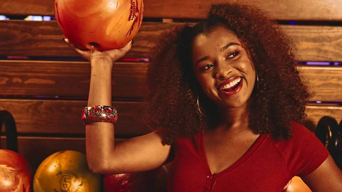 Woman holding bowling ball and smiling.