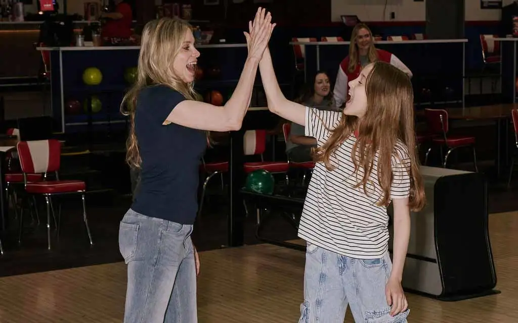 Mom and daughter high five celebrating during a game at AMF