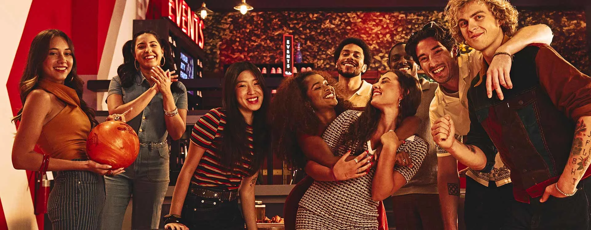Group of friends smiling and posing together with a bowling ball at a Lucky Strike bowling alley.
