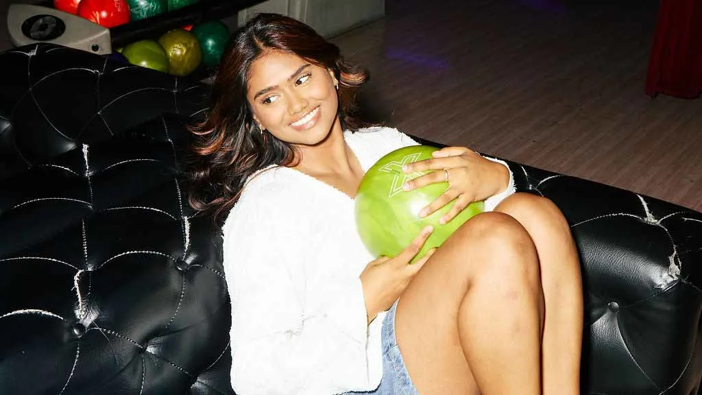 Woman holding a bowling ball on a couch at a Lucky Strike center.