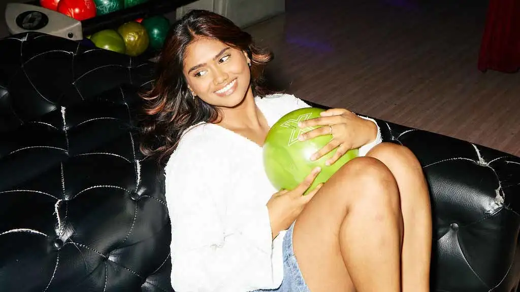 Woman holding a bowling ball on a couch at a Lucky Strike center.