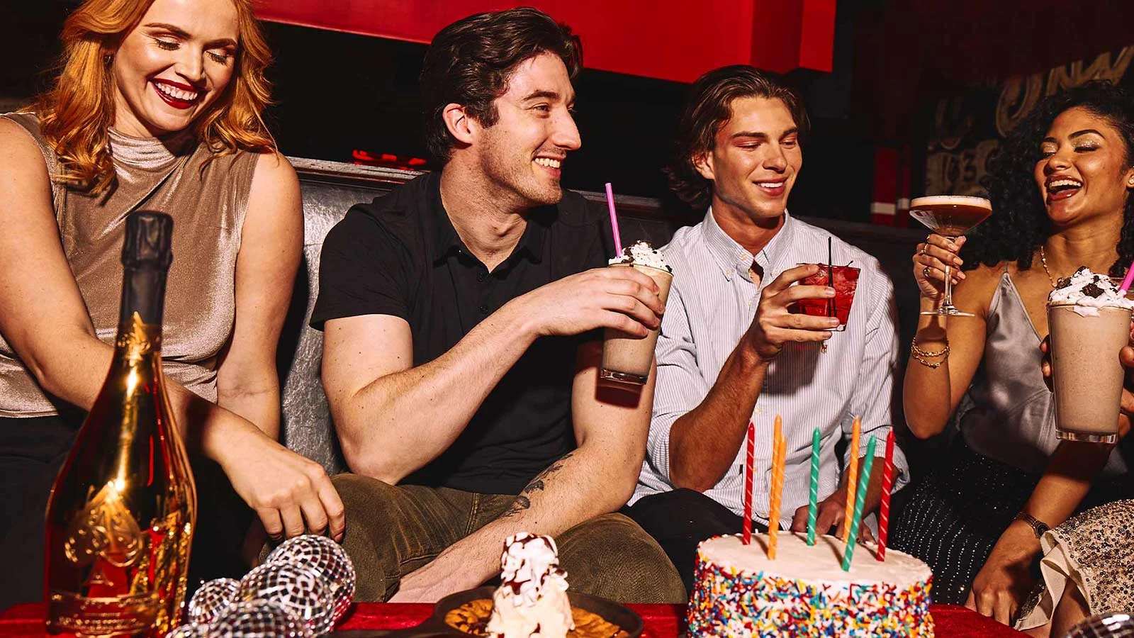 Group of friends enjoying drinks and a birthday cake