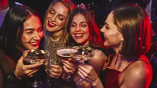 Group of women celebrating with cocktails at Lucky Strike, toasting together in a lively nightlife environment.