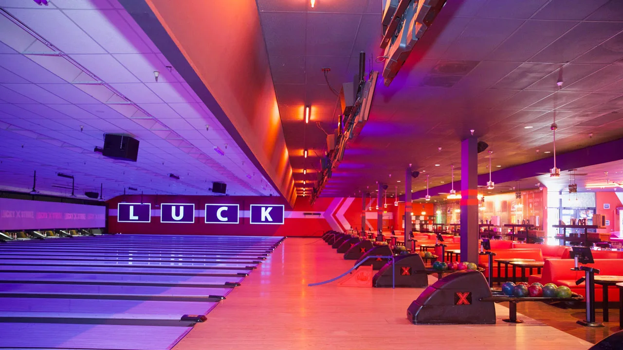 Beautiful bowling lanes with black lights and large TV screens above the lanes.
