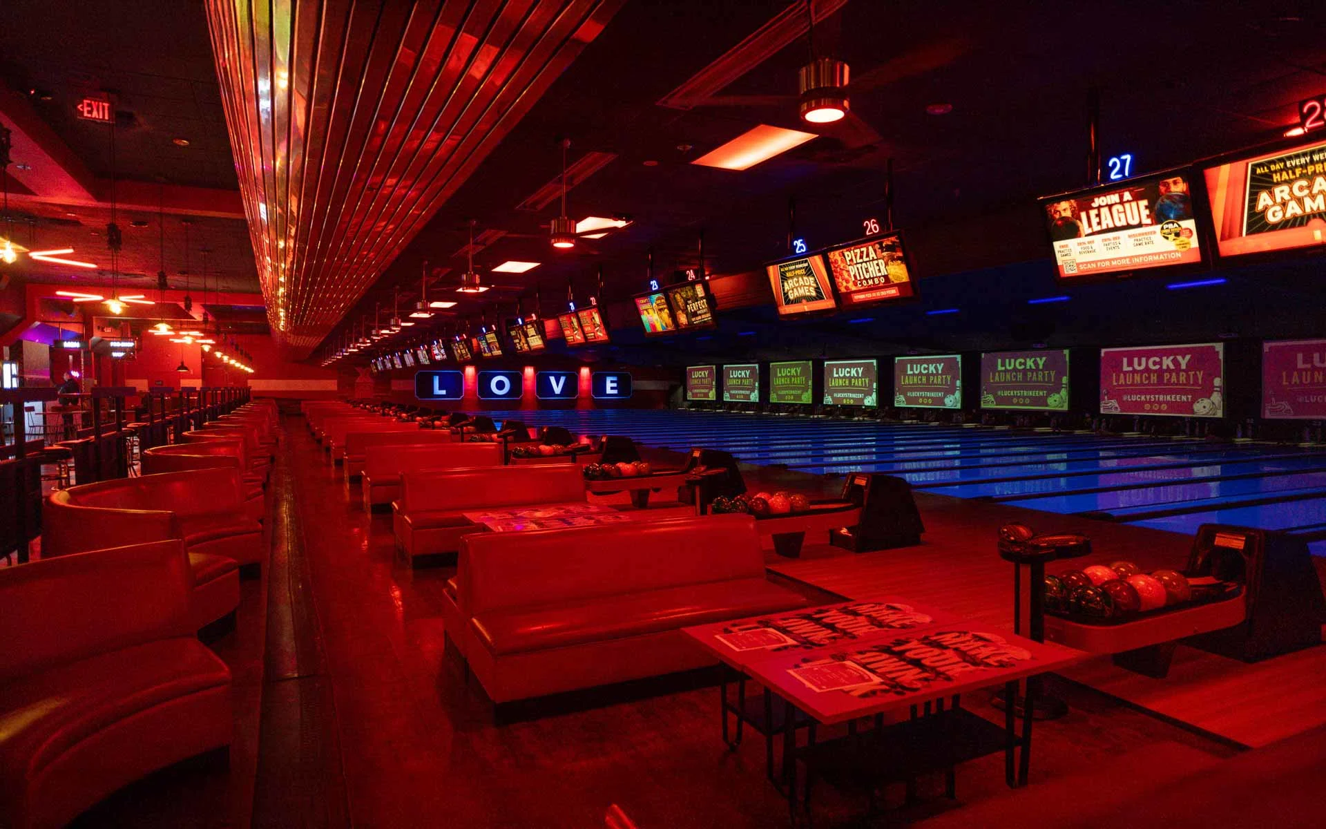 Expansive bowling lounge with plush red seating, lane-side tables, and a lively neon ambiance ideal for groups and social gatherings.