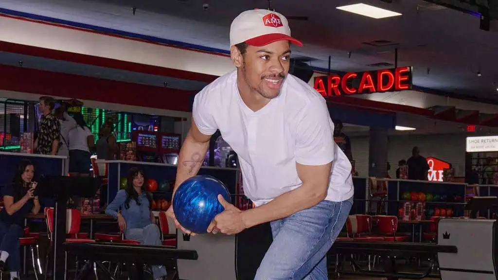 Man in AMF cap winding up to throw a blue bowling ball