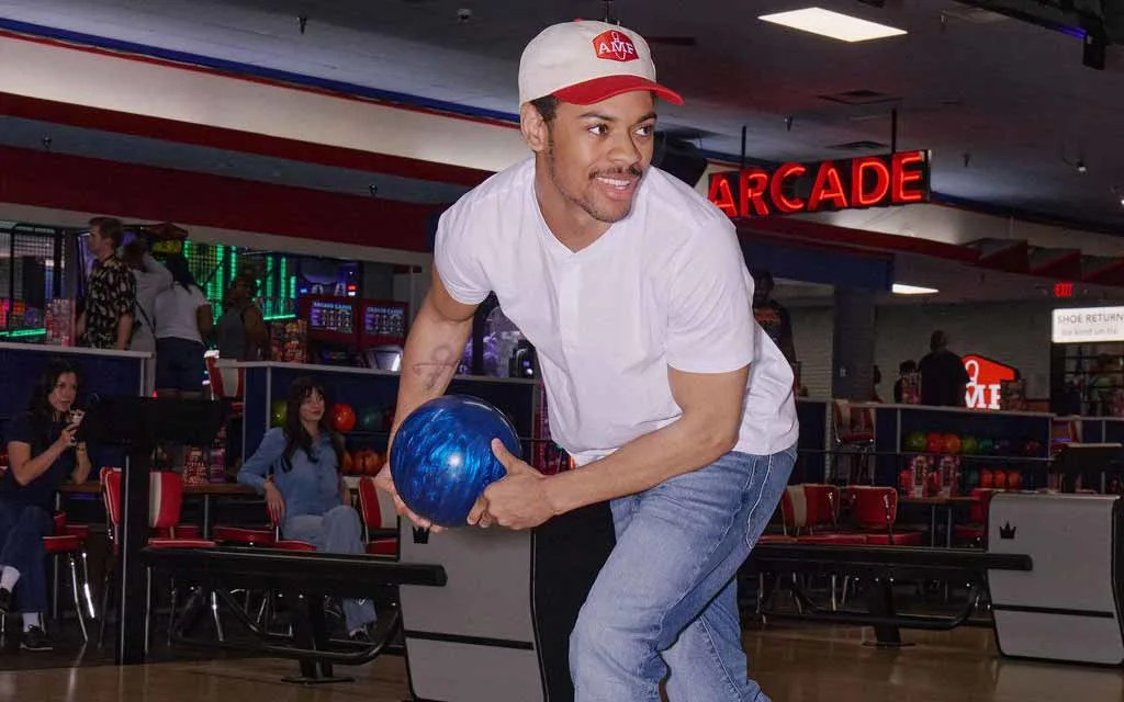 Man in AMF cap winding up to throw a blue bowling ball