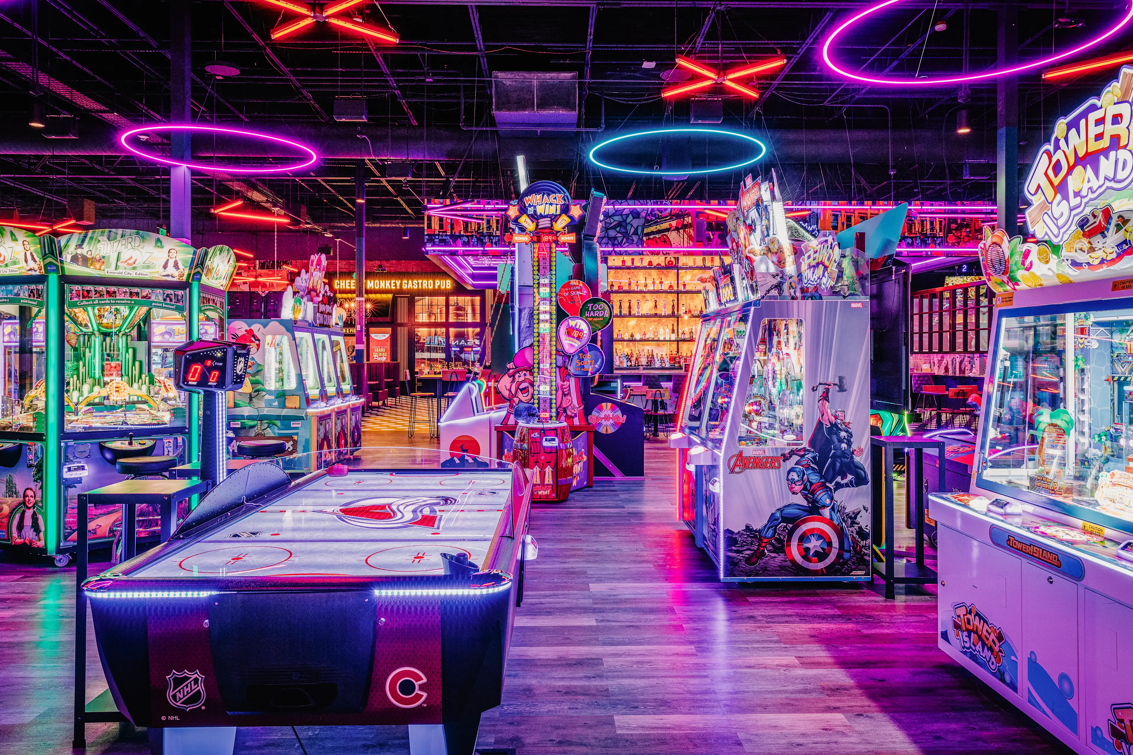 Lucky Strike arcade featuring air hockey, claw machines, and a lively bar with neon lighting.