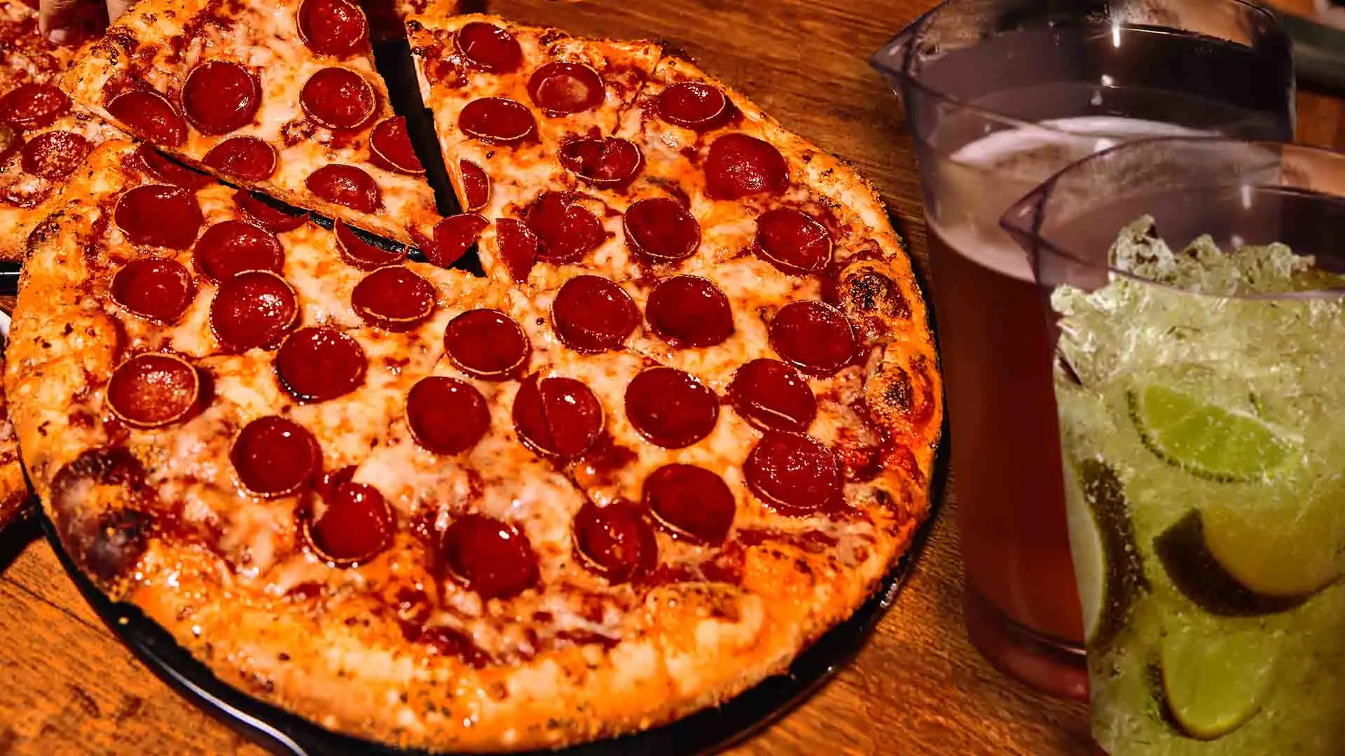 Pepperoni pizza with a pitcher of beer and pitcher of margaritas