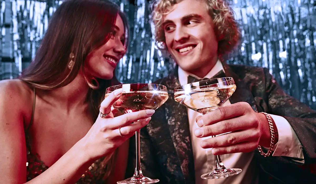 Two people cheersing champagne while smiling.