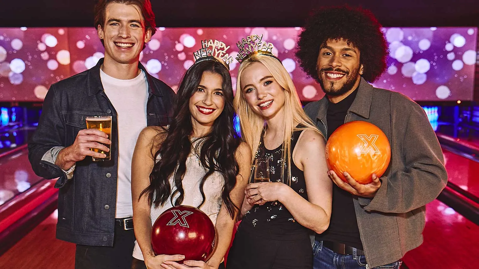Group of four friends with New Year tiaras standing in front on bowling lanes