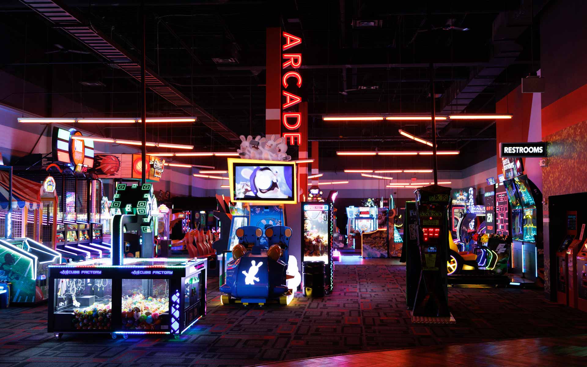 High-energy arcade filled with modern and classic games, glowing neon accents, and immersive lighting. Features a mix of skill games, racing, and interactive attractions, creating a vibrant, all-ages entertainment zone.