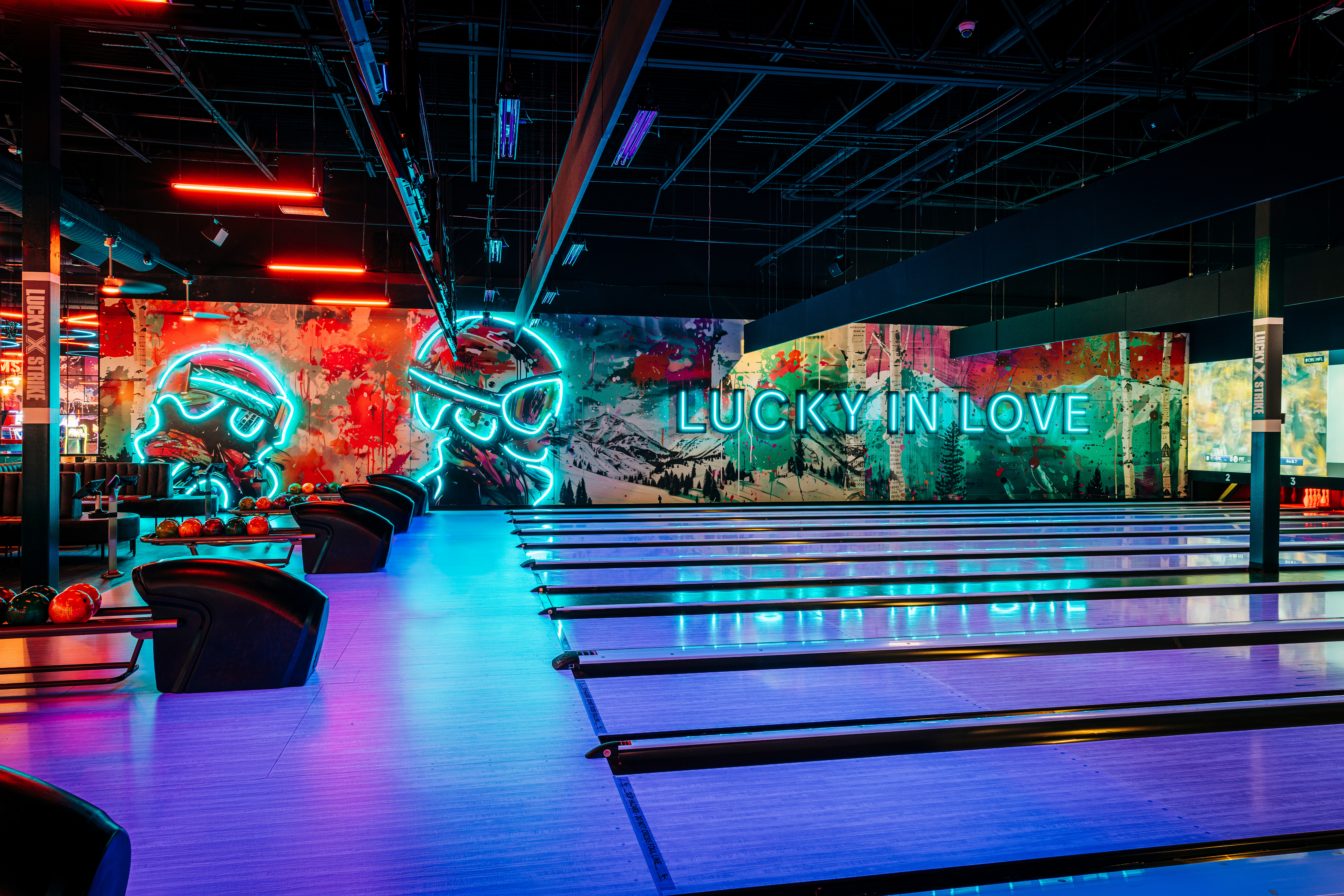 Neon-lit bowling lanes at Lucky Strike with vibrant wall art and a modern nightlife atmosphere.