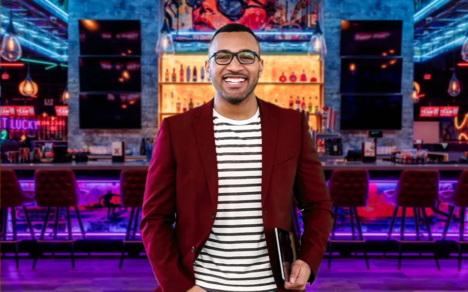 Man wearing a red dress jacket with a nice bar in the background.