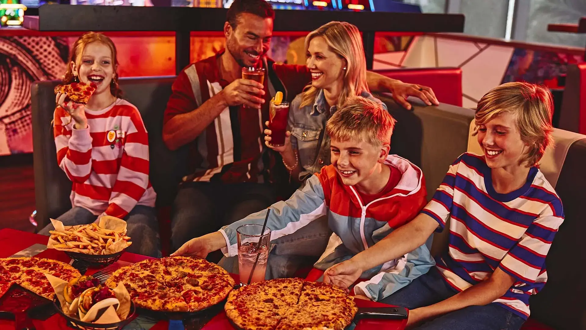 Family enjoying pizza and drinks in a large, comfortable booth