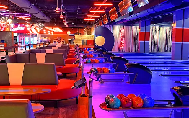 Row of colorfully lit bowling lanes and ball returns