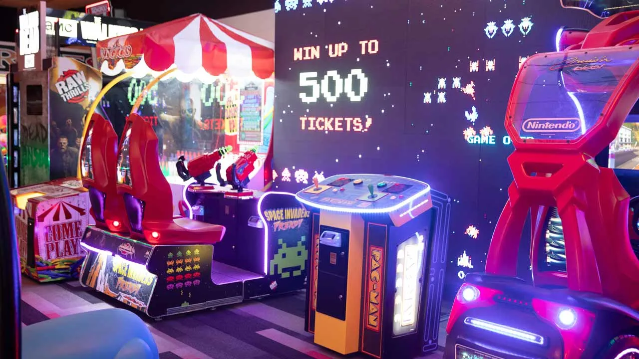 Arcade area at Lucky Strike Boca Raton featuring Space Invaders, Pac-Man, and racing games with a large screen displaying 'Win Up to 500 Tickets'.