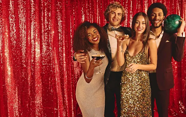 Group of four bowlers in formal wear in front of a red background