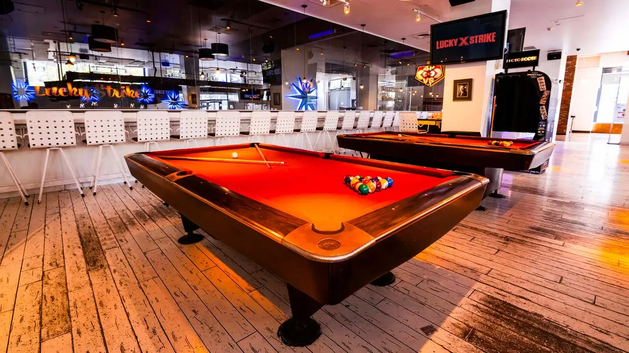 Red billiards tables in a spacious room with wood floors.