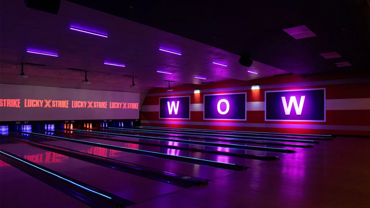 Beautiful bowling lanes with black lights and large TV screens above the lanes.