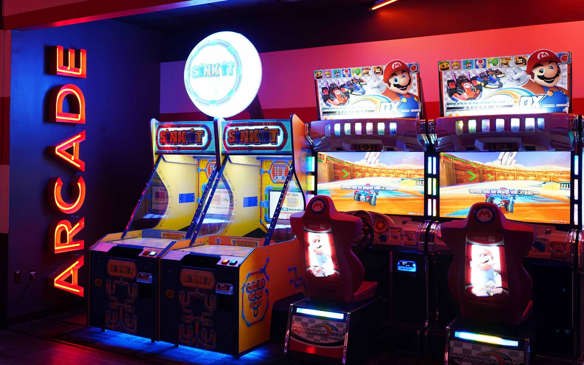 Arcade area at Lucky Strike featuring Mario Kart racing games and “Sink It” machines with bright neon lighting and bold signage.