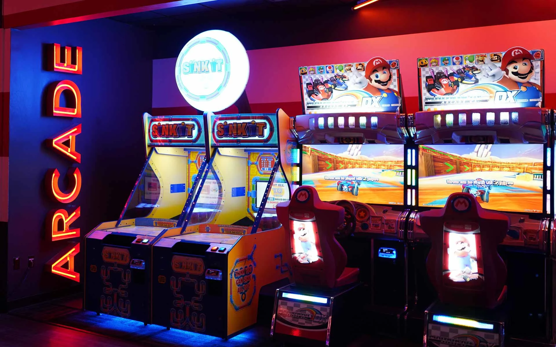 Arcade area at Lucky Strike featuring Mario Kart racing games and “Sink It” machines with bright neon lighting and bold signage.