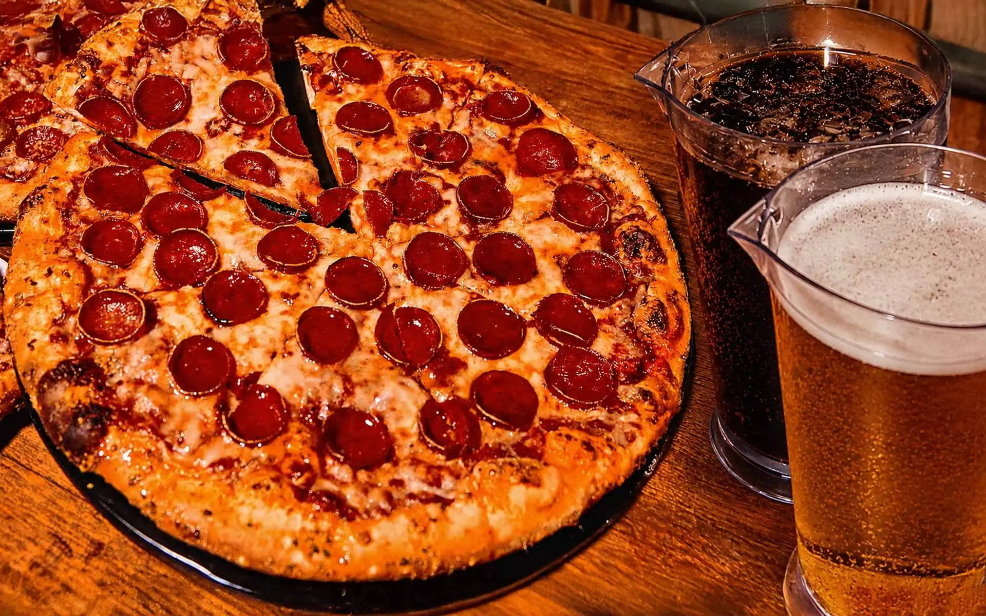 Pepperoni pizza with pitchers of soda and beer