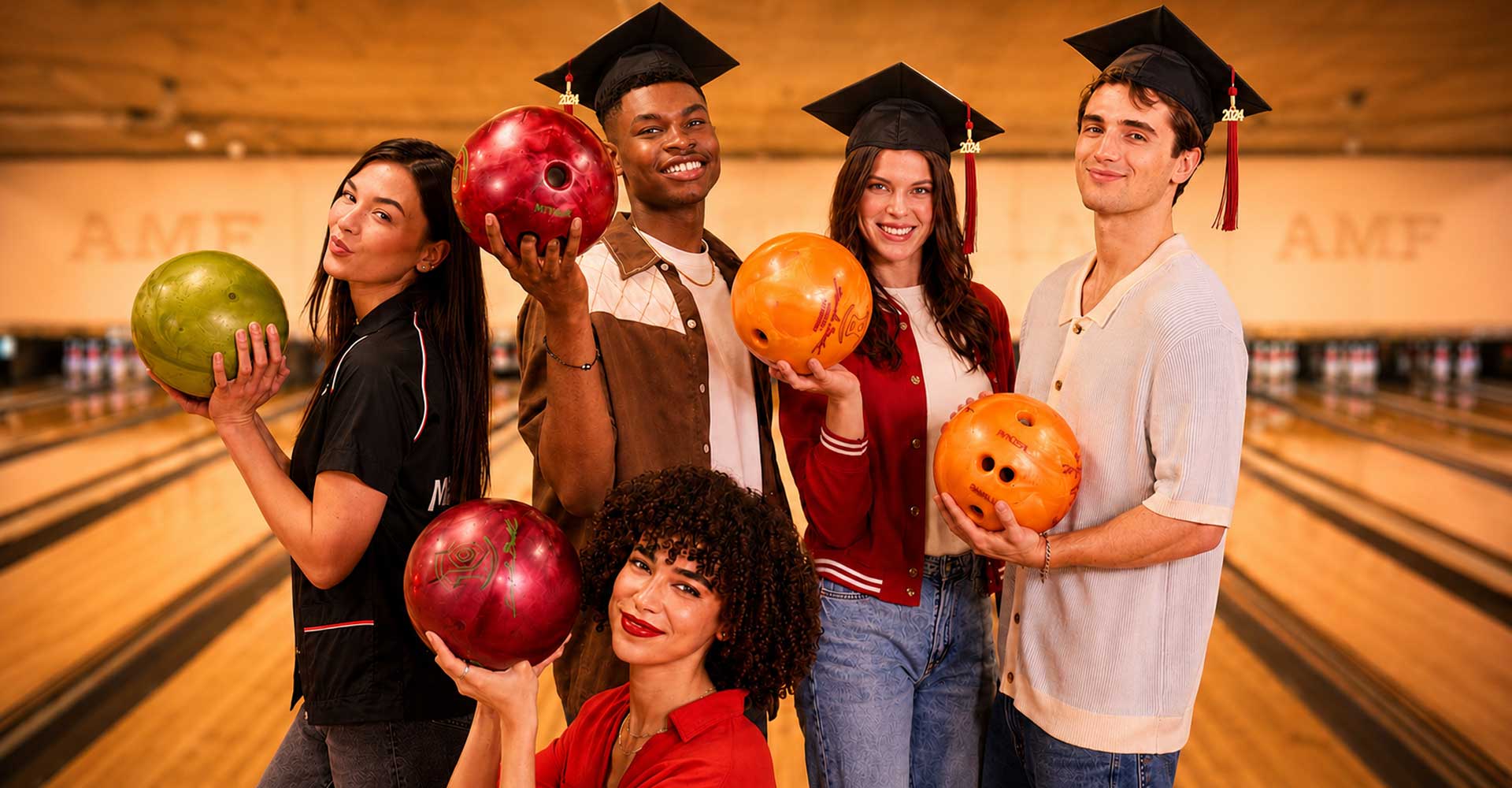 Group of recent college graduates posing with colorful bowling balls inside an AMF bowling alley in a warm, celebratory atmosphere.