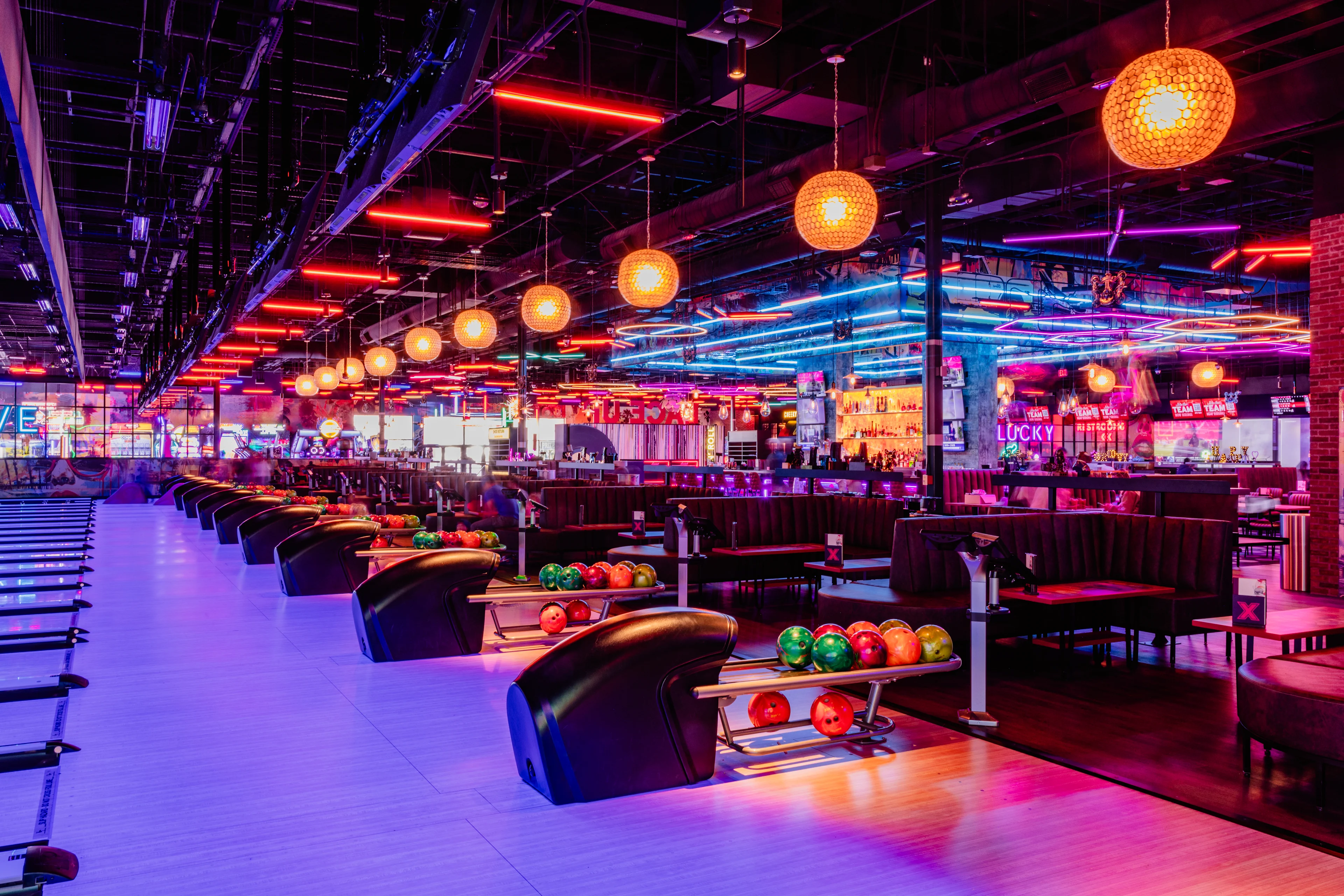 Upscale bowling lanes at Lucky Strike with lounge seating, full bar, and immersive neon lighting.