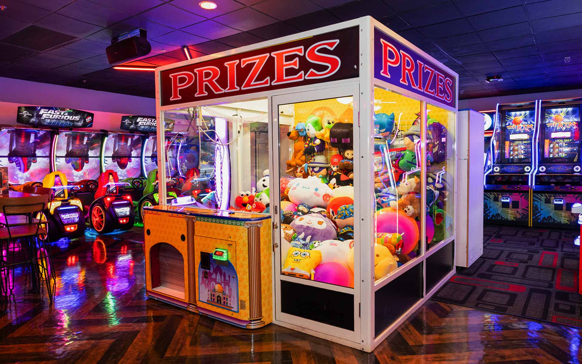 Lucky Strike arcade prize machine filled with plush toys, surrounded by neon-lit racing games and interactive entertainment attractions.