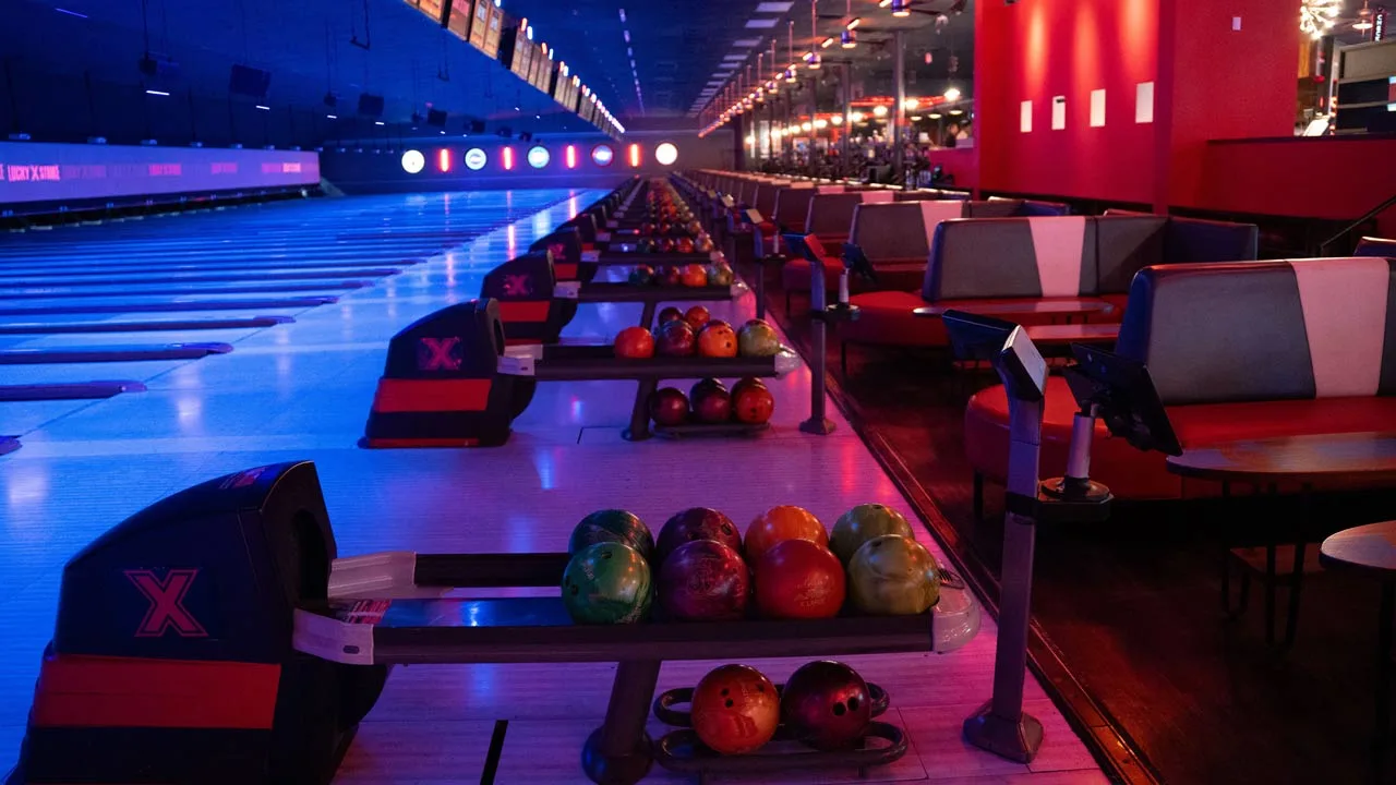 Beautiful bowling lanes with black lights and large TV screens above the lanes.
