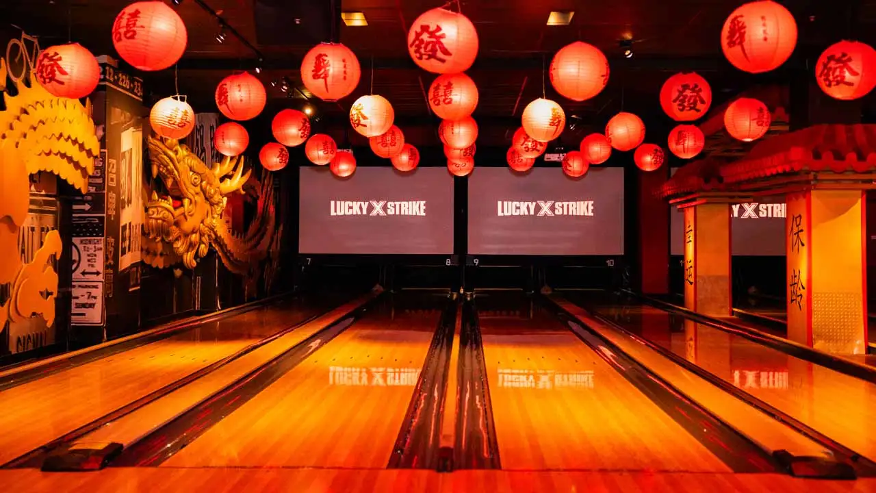 Bowling lanes decorated with red lanterns and dragon artwork, featuring Lucky Strike scoring screens in a vibrant themed entertainment venue.