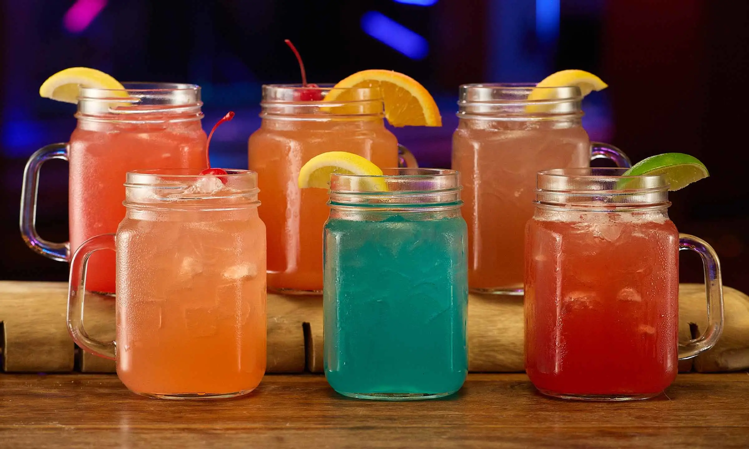 Six colorful drinks with lemons, limes, and cherries
