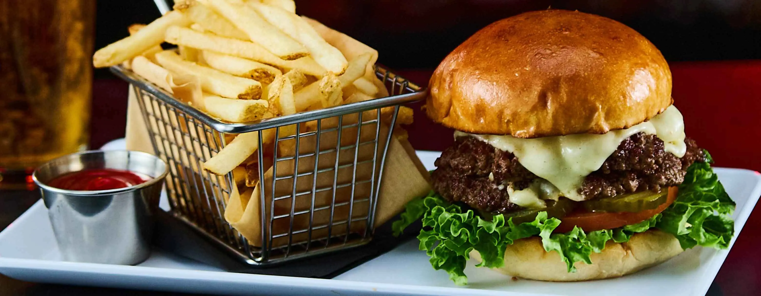 Delicious cheeseburger and basket of fresh french fries with a side of ketchup.