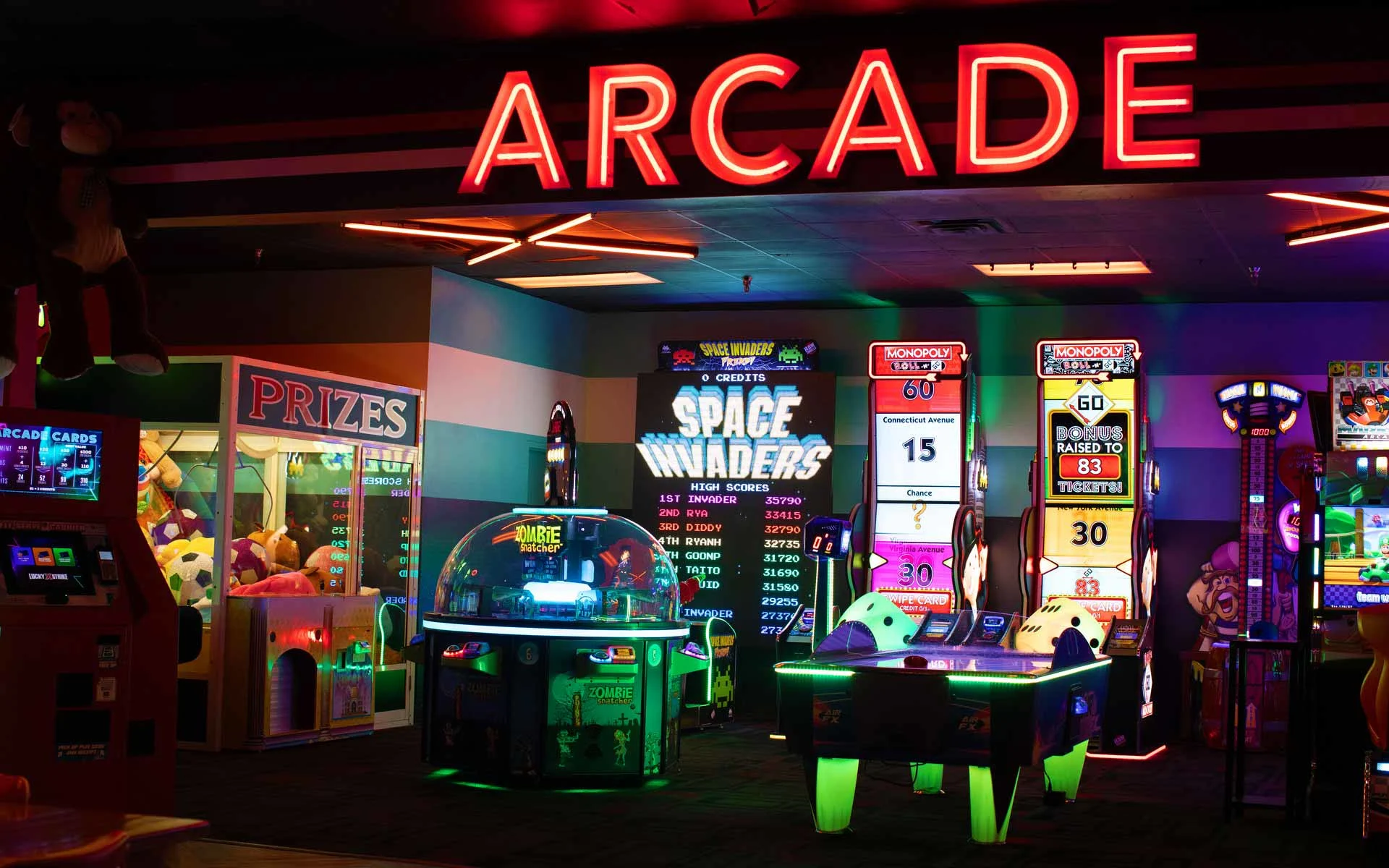 Lucky Strike arcade entrance with neon “ARCADE” sign, prize machines, and classic games in a vibrant gaming area.