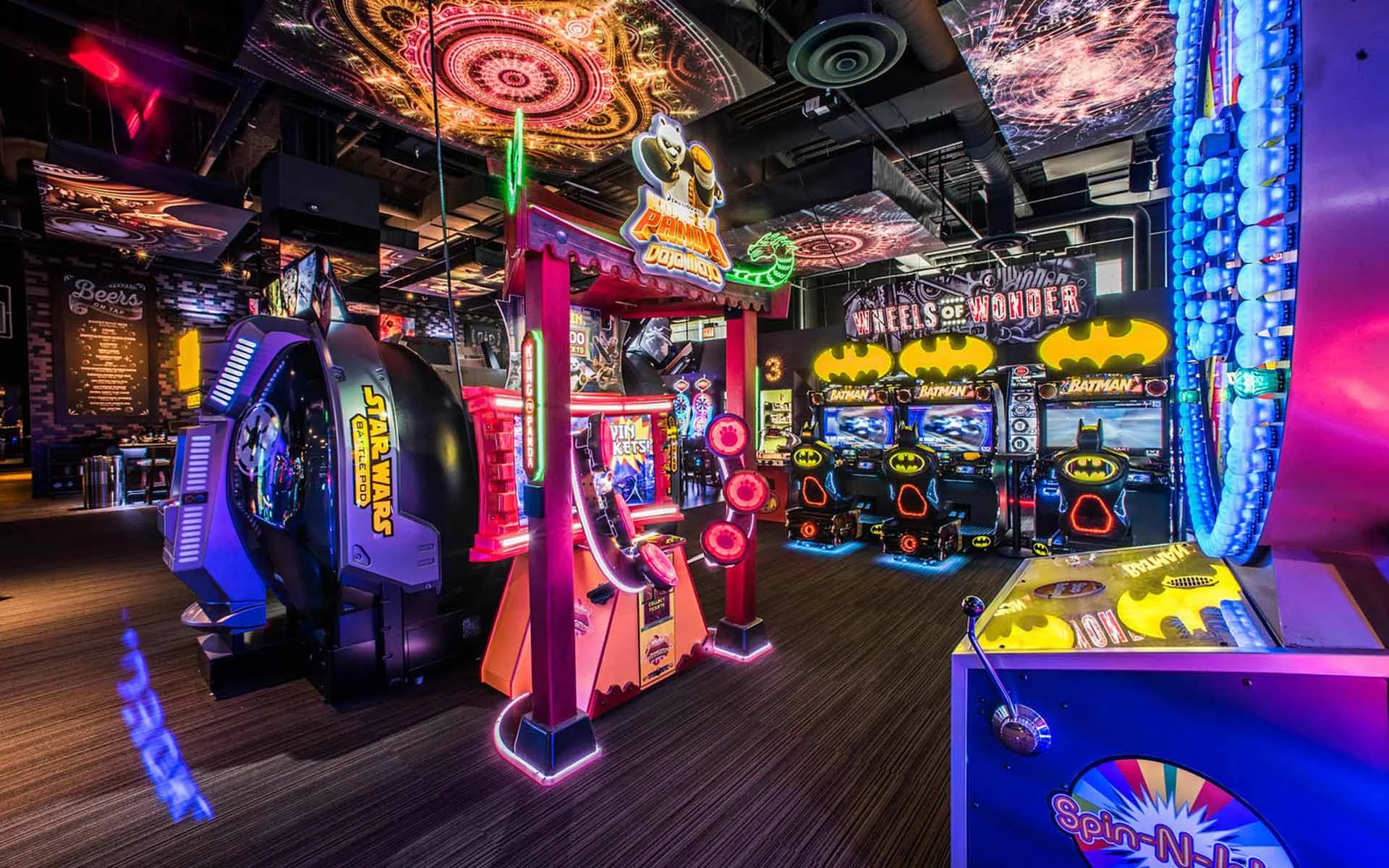 Vibrant arcade at Lucky Strike featuring immersive ceiling visuals, colorful game machines, and popular attractions like racing and superhero-themed games.
